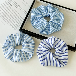 Drei-teiliges Set aus blau-weißen Haargummis mit eleganten Falten auf einem Tablett