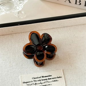 Détail d'une pince à cheveux fleur vintage ambre et noire sur un fond de texture