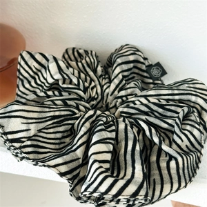 Elegant zebra striped oversized hair scrunchie with a floral logo tag on white background
