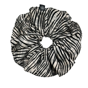 Elegant zebra striped hair scrunchie with a small logo tag on a clean white background