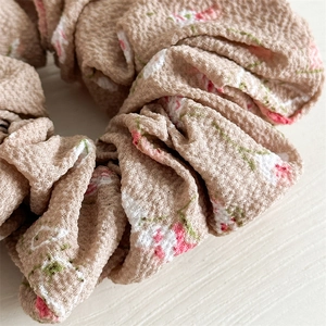 Détail macro du chouchou en mousseline avec motif floral et texture froissée à bulles
