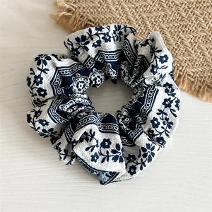Vue détaillée de la texture du tissu en mousseline et du motif à rayures bleues du chouchou