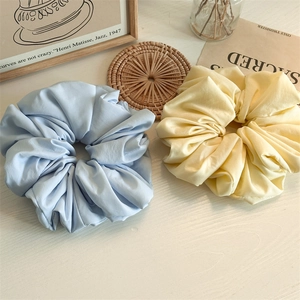 Detailed texture of cream and light blue oversized cloud scrunchies on a wooden surface
