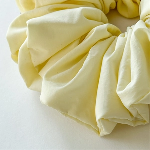 Detailed macro view of soft cream cloud scrunchie with delicate fabric texture
