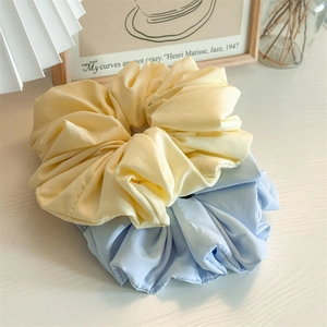 Close-up of large ruffled fabric scrunchies in cream yellow and soft blue colors