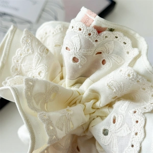 Macro shot of off-white cream hair scrunchie with intricate lace embroidery and pink lining