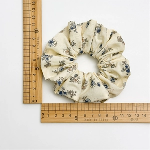 Chouchou fleuri beige de grande taille présenté avec une règle pour mesurer le diamètre