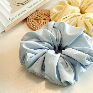 Close-up of light blue and yellow oversized scrunchies showing soft matte fabric texture