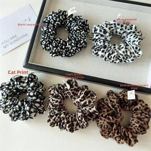 Close-up of five leopard print scrunchies featuring luxury handmade labels and satin texture