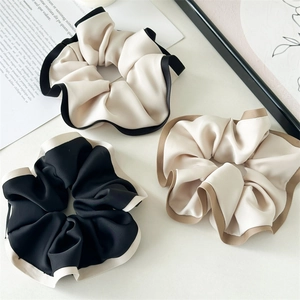 Three elegant satin scrunchies with contrasting edges displayed on a white surface