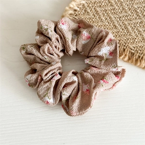 Gros plan d'un chouchou en mousseline avec imprimé floral rouge sur tissu kaki clair