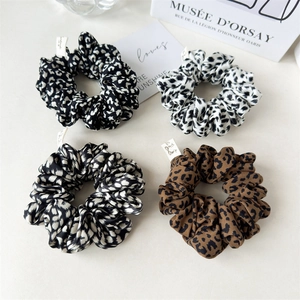 Set of four leopard print scrunchies in diverse colors for elegant hair styling