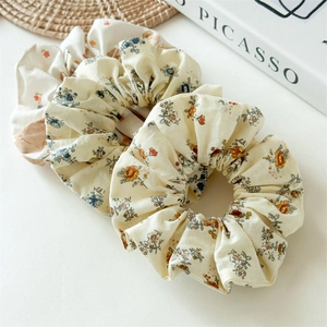 Lot de chouchous à fleurs beige et crème en coton sur un plateau de présentation