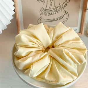 Macro detail of large cream yellow scrunchie with soft pleated texture on a tray