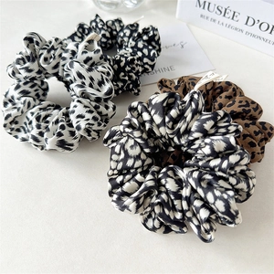 Set of four leopard print scrunchies in various patterns and colors on a clean background