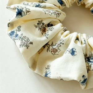Détail du chouchou floral avec motifs de baies bleues et brunes sur tissu de couleur beige