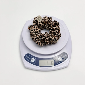 Detail showing a leopard print hair scrunchie being weighed on a scale at 11.6 grams