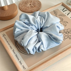 Macro shot of large light blue ruffled scrunchie on a decorative wooden frame backdrop