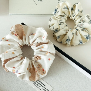 Détail de deux chouchous en tissu floral avec des motifs d'ours et de fleurs vintage