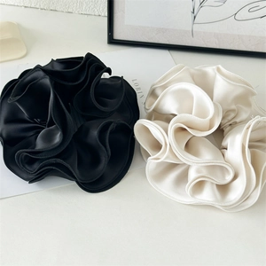 Detail view of large satin scrunchies in black and beige with ruffle edges