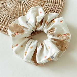 Détail d'un chouchou floral avec motifs d'ours sur un fond rustique en rotin tressé