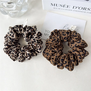 Close-up of leopard print hair scrunchies with soft pleated texture and aesthetic props