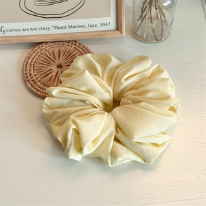 Elegant cream yellow oversized scrunchie made of premium matte fabric on a minimalist desk