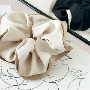 Close-up of beige and khaki contrast color satin scrunchie with rich pleated texture