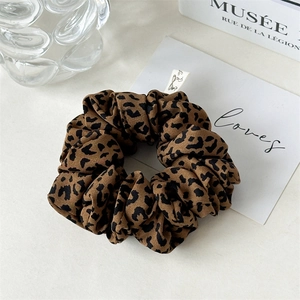 Detail view of leopard print scrunchie made of chiffon fabric with small woven label