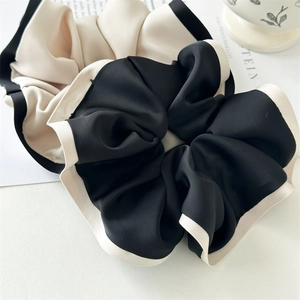 Detail of elegant two-tone scrunchies in black and cream satin fabric texture