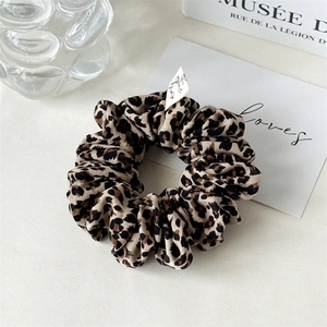 Detailed view of leopard print scrunchie made of silky fabric with premium pleated texture