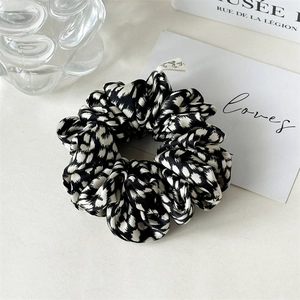 Detail of silk satin scrunchie featuring black and white abstract leopard print pattern