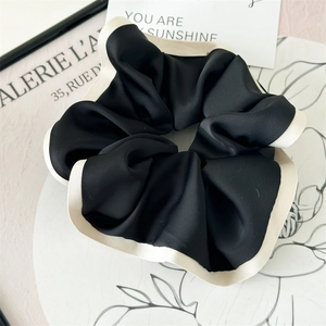 Detail of elegant black and cream silk scrunchie with soft pleats and smooth texture