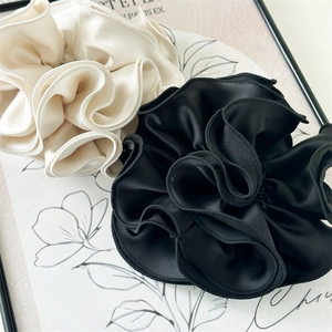 Detail of silk satin scrunchies with elegant ruffled edges in black and cream white colors