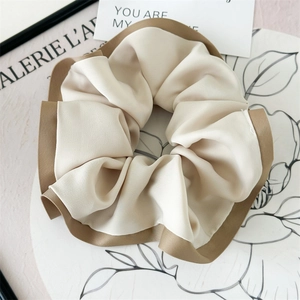 Detailed view of bicolor satin scrunchie with cream center and khaki edges