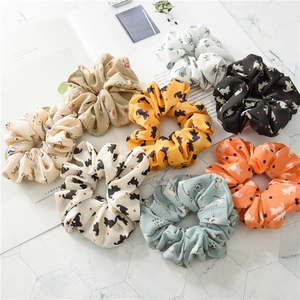 Set of 8 floral and cat print fabric scrunchies in various colors on a marble background