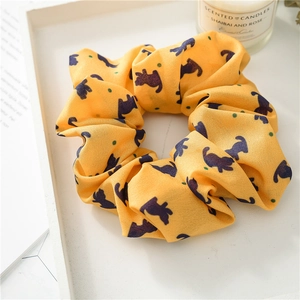 Yellow scrunchie with cute cat prints and dots displayed on a stylish tray