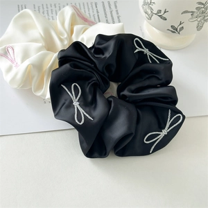 Detail view of satin scrunchies with delicate butterfly embroidery in black and beige