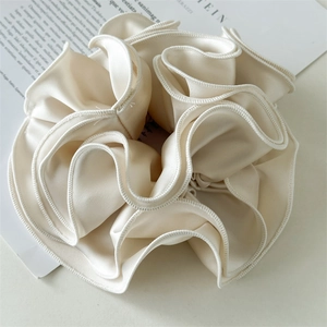 Detailed macro view of cream satin scrunchie featuring elegant ruffled edges and silky texture