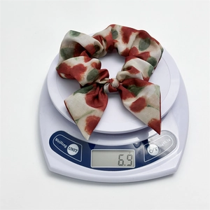 Vue détaillée d'un chouchou en mousseline tie-dye avec nœud pesant 6,9 g sur balance