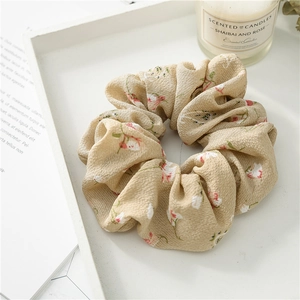 Detailed texture of beige floral scrunchie with red flowers in a soft aesthetic tray