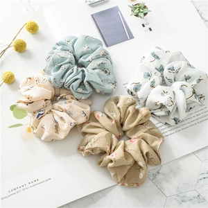 Close-up of four floral print fabric scrunchies in blue, white, beige and brown tones