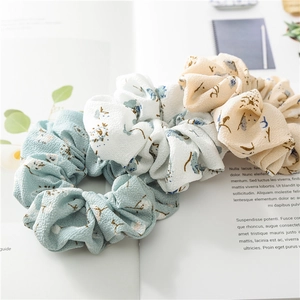 Three-pack floral scrunchies in sky blue and beige on a magazine for a fresh aesthetic look