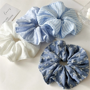Set of four textured blue and white scrunchies with embroidery and plaid patterns