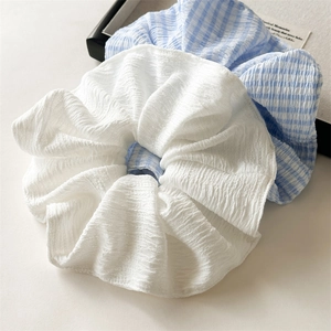 Close-up of white and blue plaid oversized hair scrunchies with pleated texture detail