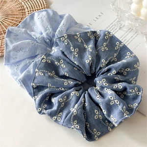 Detailed view of large embroidered scrunchies in light blue and denim blue floral fabric