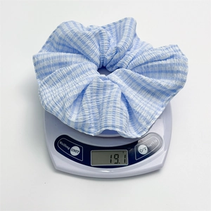 Blue and white checkered fabric scrunchie being weighed at 19.1g on a digital scale