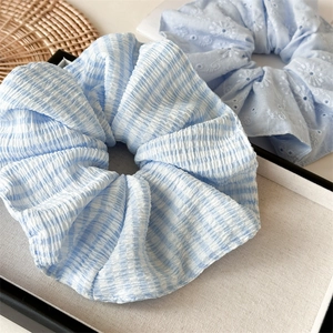 Close-up of light blue seersucker striped scrunchie and floral embroidery hair tie