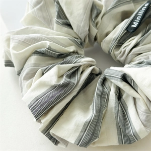 Premium black and white striped scrunchie with Miniline tag on cream background
