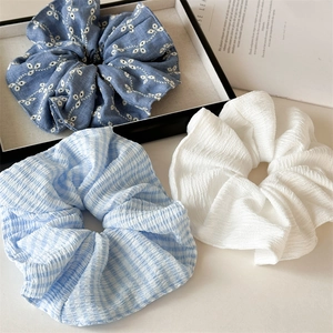 Three-piece set of large ruffled hair scrunchies in blue floral, plaid, and white fabric
